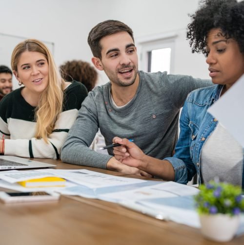 Young creative designers working in a project and discussing new order development on workplace. Business and team work concept.