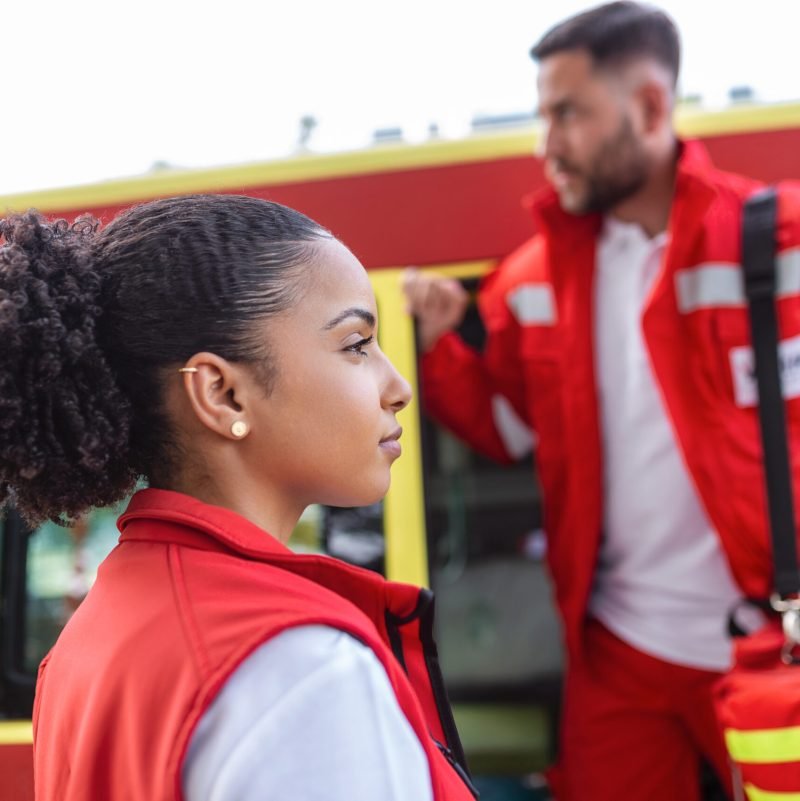Paramedic nurse and emergency doctor at ambulance with kit. a paramedic, standing at the rear of an ambulance, by the open doors.