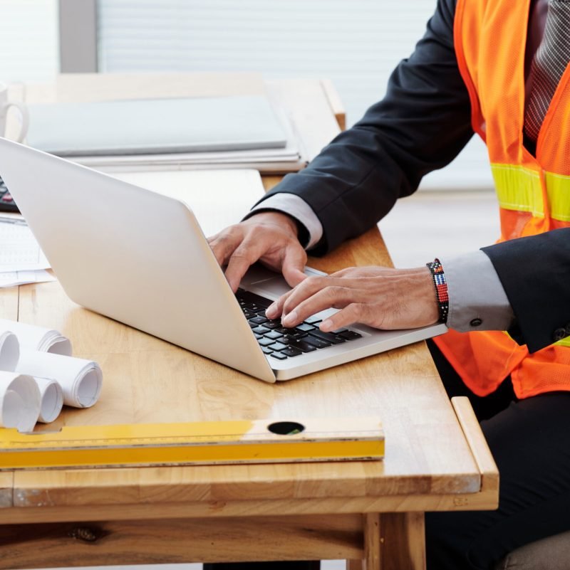 Cropped image of engineer working on laptop in his office